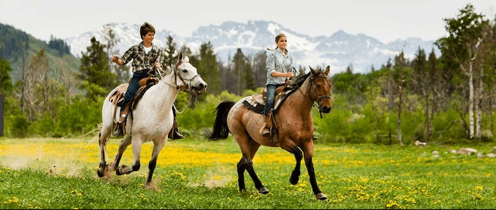 Confident plus-size woman riding Robroyston a horse through a field with a smile on her face.